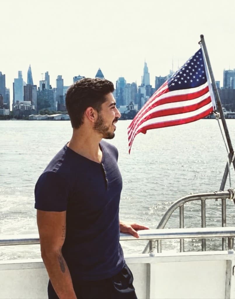 Khalil Zlaoui on a boat, with the New York skyline and an American flag.